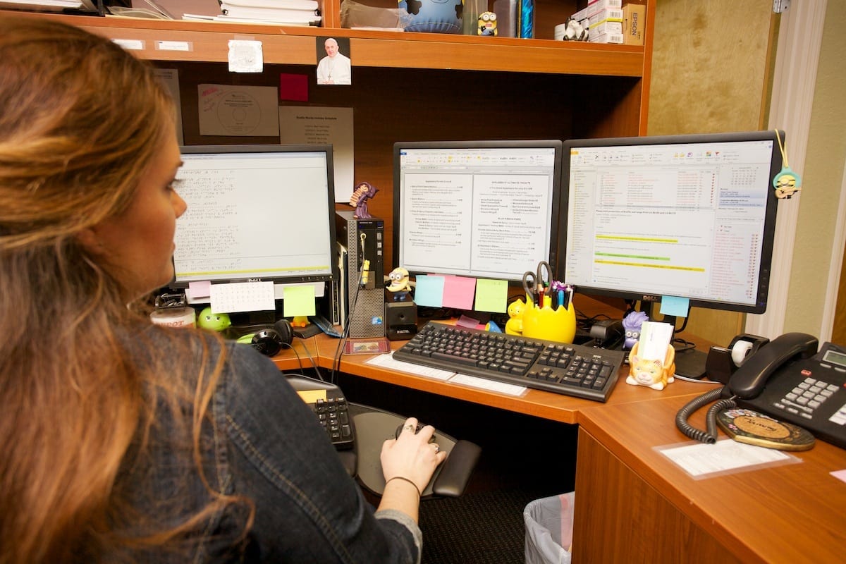 A Braille Works employee sitting at her desk transcribing a document into braille and large print.
