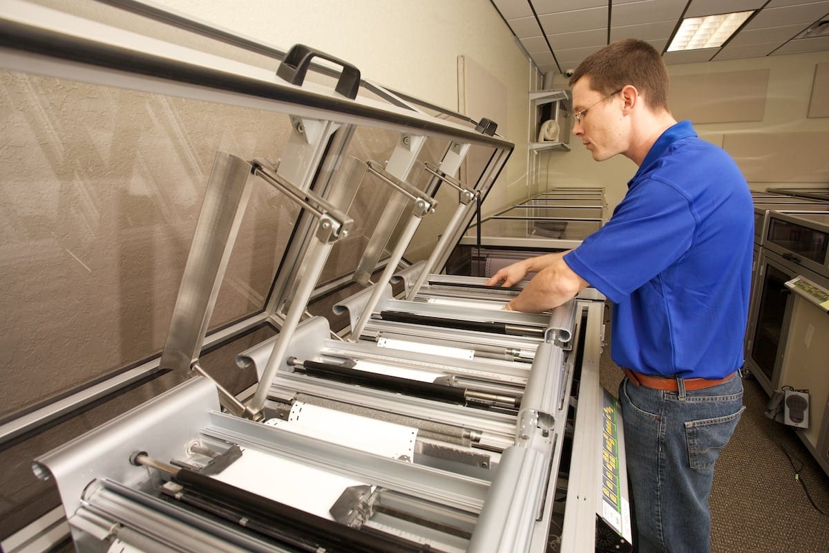 A Braille Works employee loading paper into a braille embosser.