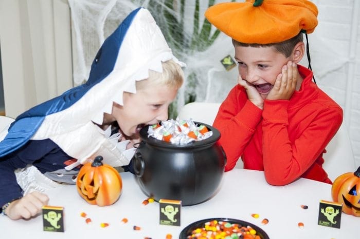 Image showing two young boys in Halloween costumes snacking on candy.