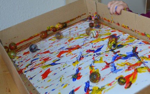 Paint covered marbles rolling around on paper, leaving paint on the paper as they roll. Paint covered marbles rolling around on paper, leaving paint on the paper as they roll.