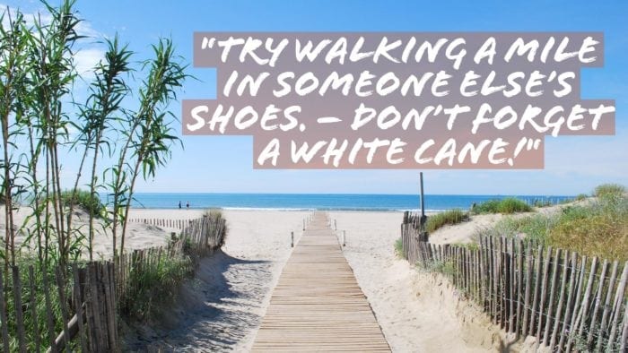 A walkway in sand heading toward a beach, with the words "Try walking in someone else's shoes. -Don't forget a white cane!"
