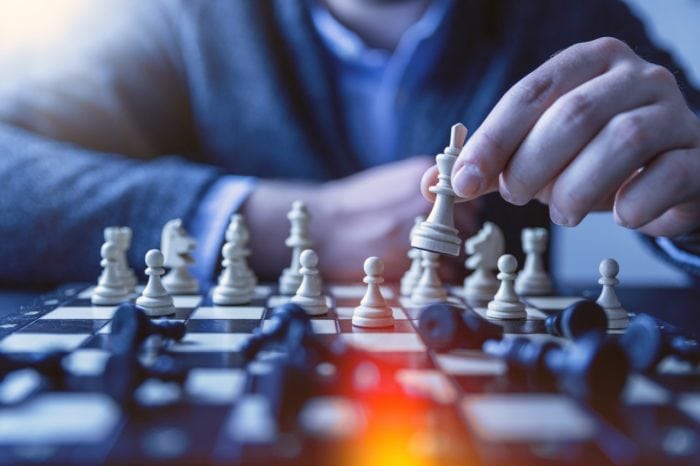 An individual playing chess and in the middle of a checkmate. 
