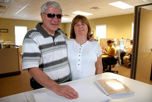 Braille Works's owners, Lou and Joyce, standing in front of a table with a braille menu at the start of the business.