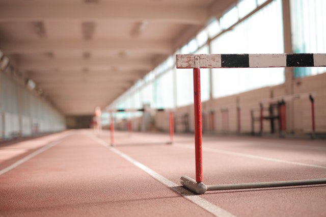 Row of striped hurdles in a gymnasium with soft lighting.