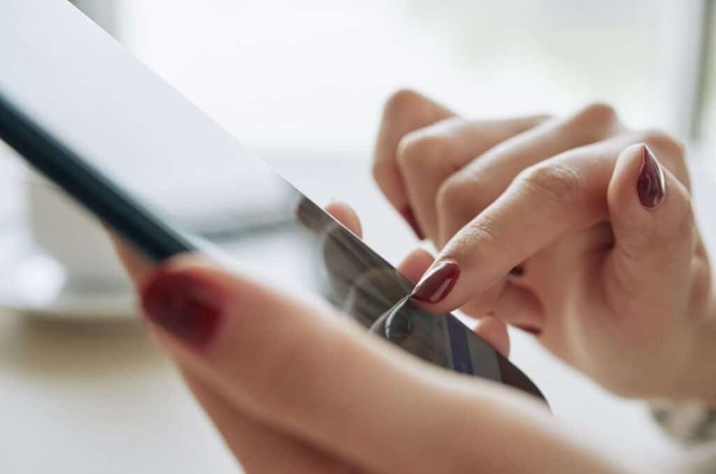 Someone holding a phone and touching the screen with their finger.