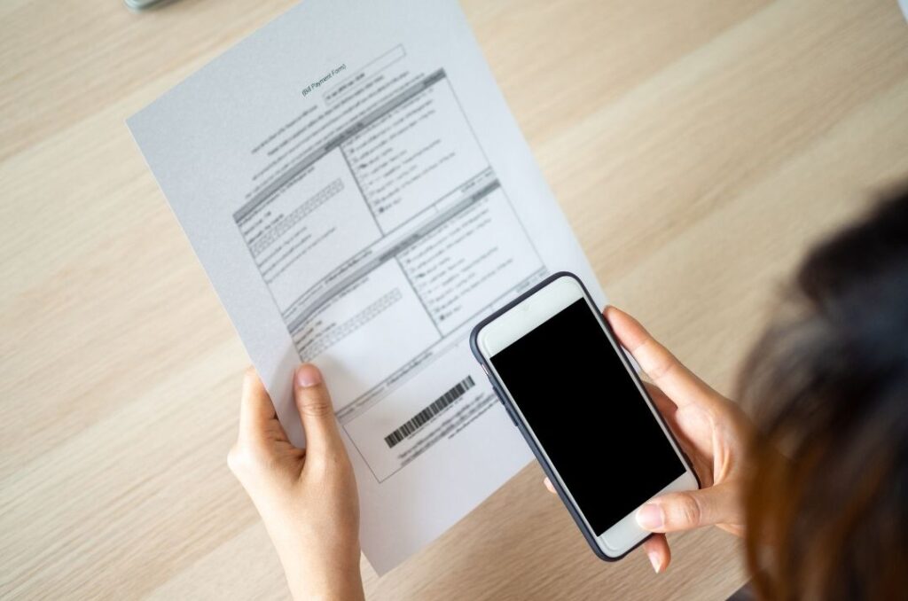 A person holding up a phone in front of a computer.